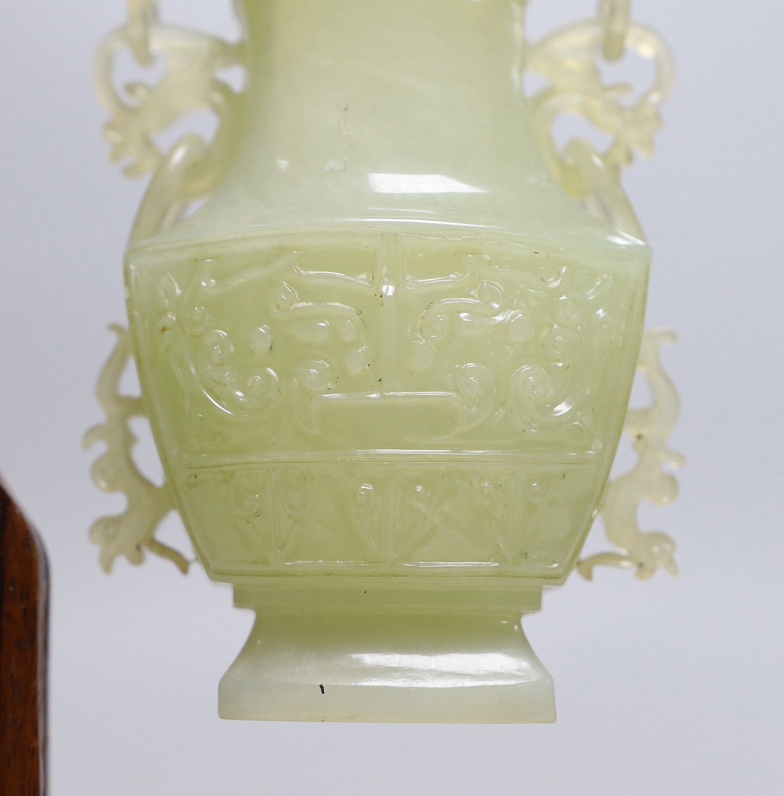 A Chinese bowenite jade hanging vase and cover together with a carved hard wood stand, one foot missing, 42cm tall